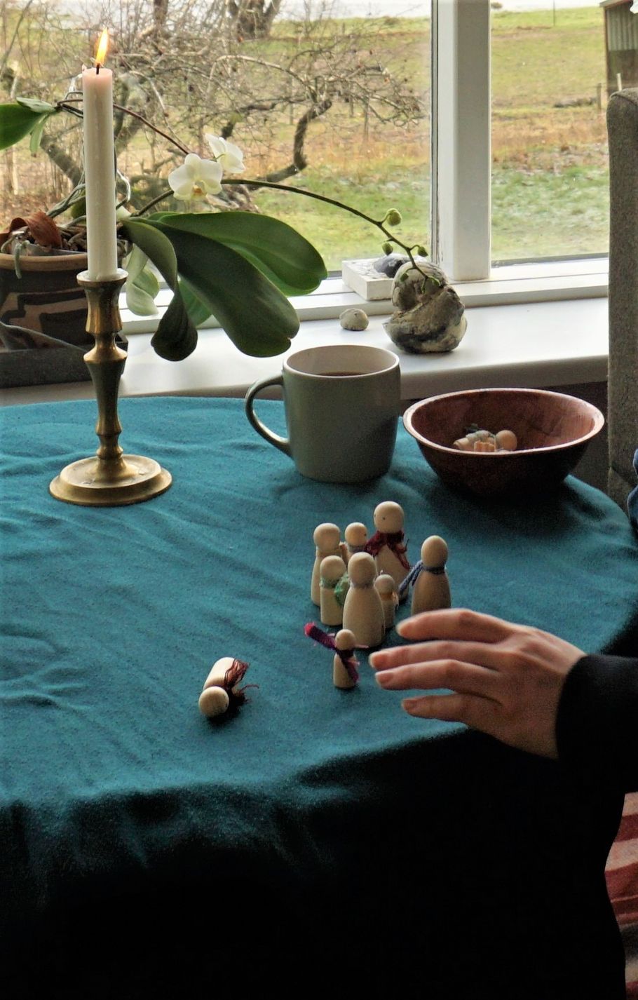 Små figurer stillet op på et bord ved et vindue, set tæt på.